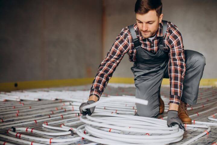 service man installing electric heating system floor